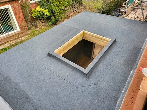 Timber-framed rooflight upstand set into a newly felted flat roof, garden below