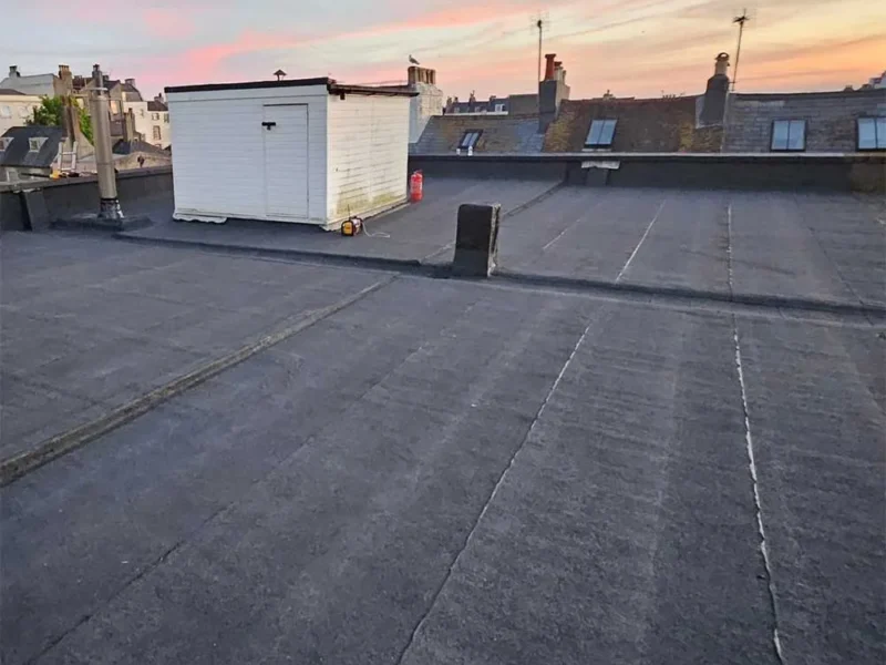 New mineral felt flat roof at sunset, pink and orange sky over the rooftops of a Sussex seaside town