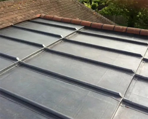 Traditional lead flat roof with clean welted rolls running to the ridge tiles