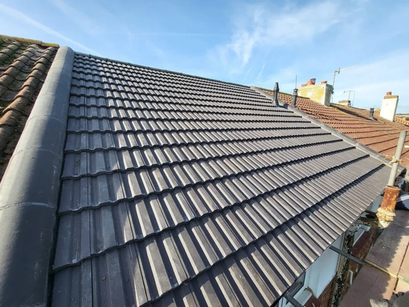 The completed roof in new dark grey interlocking tile with a dry ridge system, photographed from the scaffold
