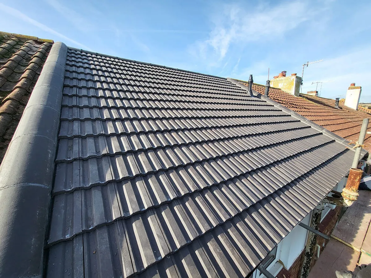 The completed roof in new dark grey interlocking tile with a dry ridge system, photographed from the scaffold