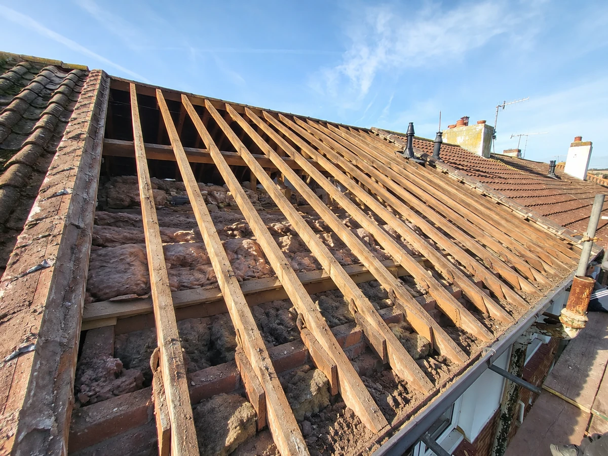 AI reconstruction of the roof stripped back to exposed timber rafters, aligned with the viewpoint of the finished roof photograph