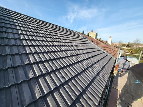 Wide view along a newly tiled roof slope with the Sussex coastline in the distance