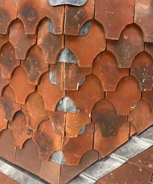 Ornamental clay bonnet hip tiles laid in a fish-scale pattern