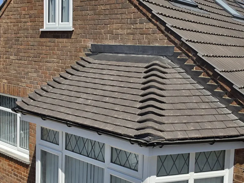 Clay tile hip roof over a bay window, conservatory roof visible below