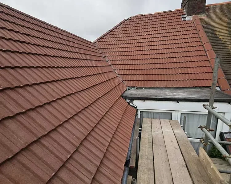 New red concrete tile roof with hip valley and a chimney with pots, viewed from the scaffold boards